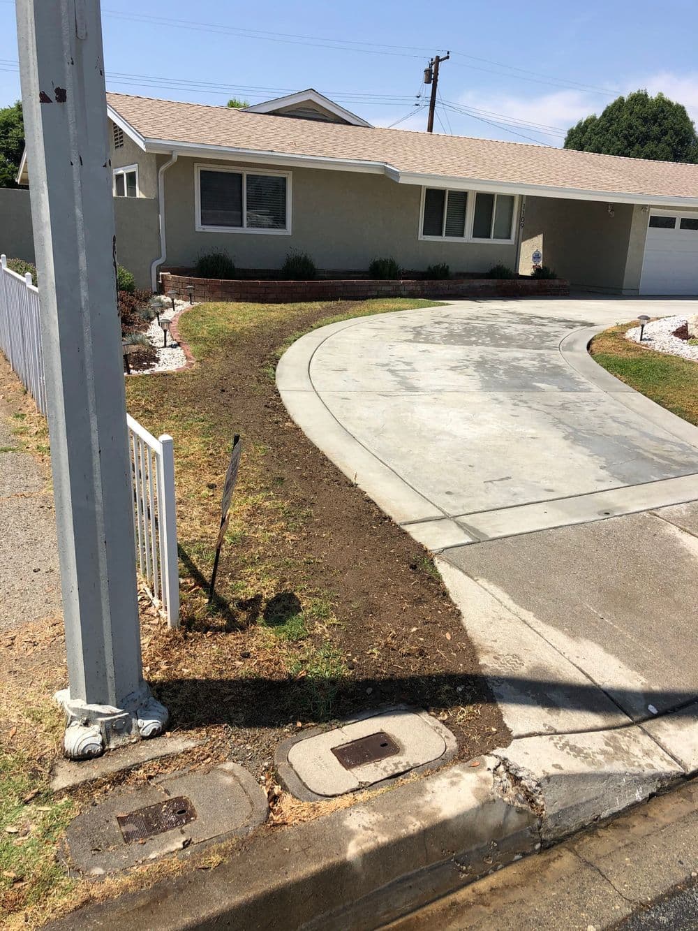 Freshly landscaped front yard with new driveway and decorative path beside a suburban home.