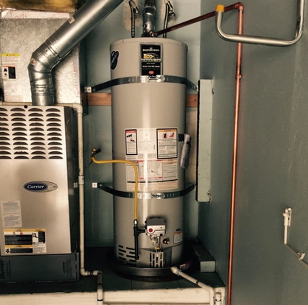 Residential water heater and HVAC unit in a utility room with copper piping and venting.